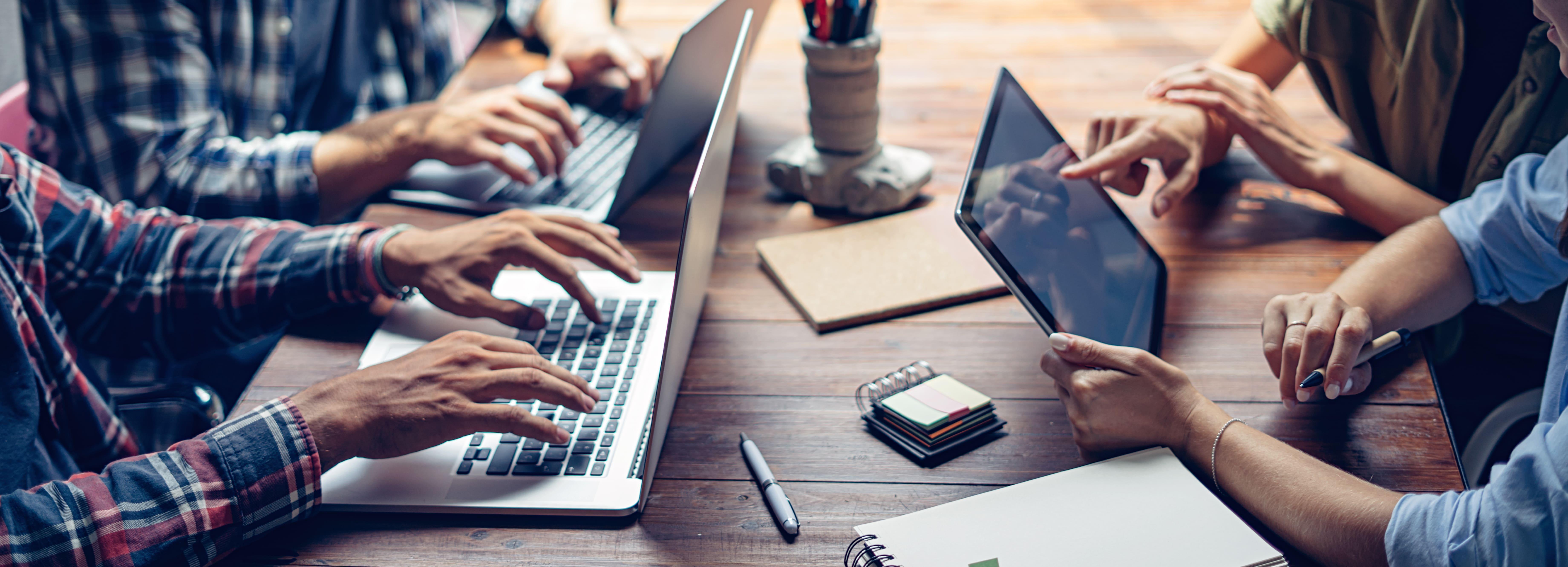 Digital marketing students working together on laptops and tablets during a BA (Hons) course project.