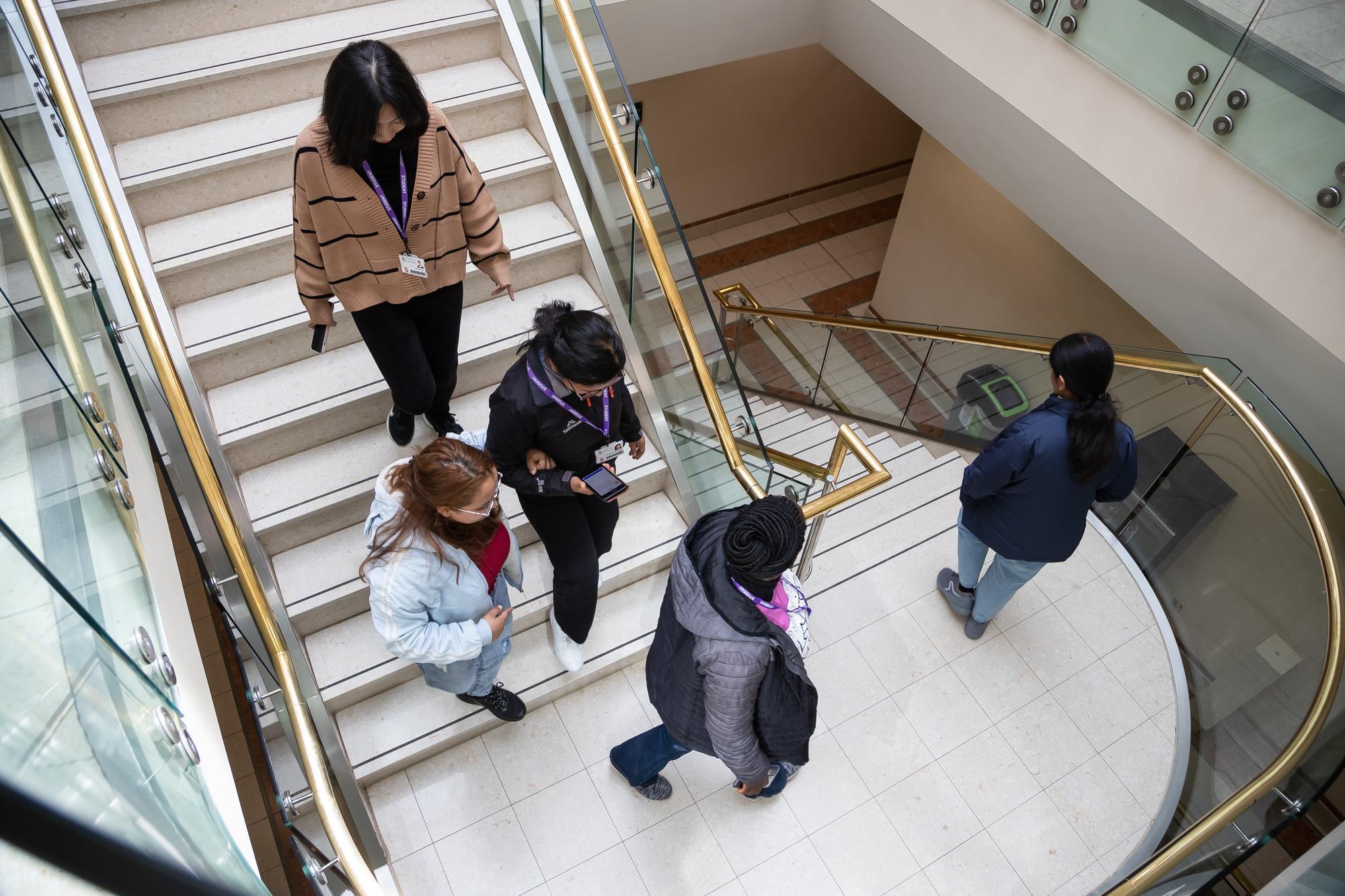 Students walking together inside a modern university building, representing collaboration, networking, and skills development for Business Management and Marketing BA Hons.