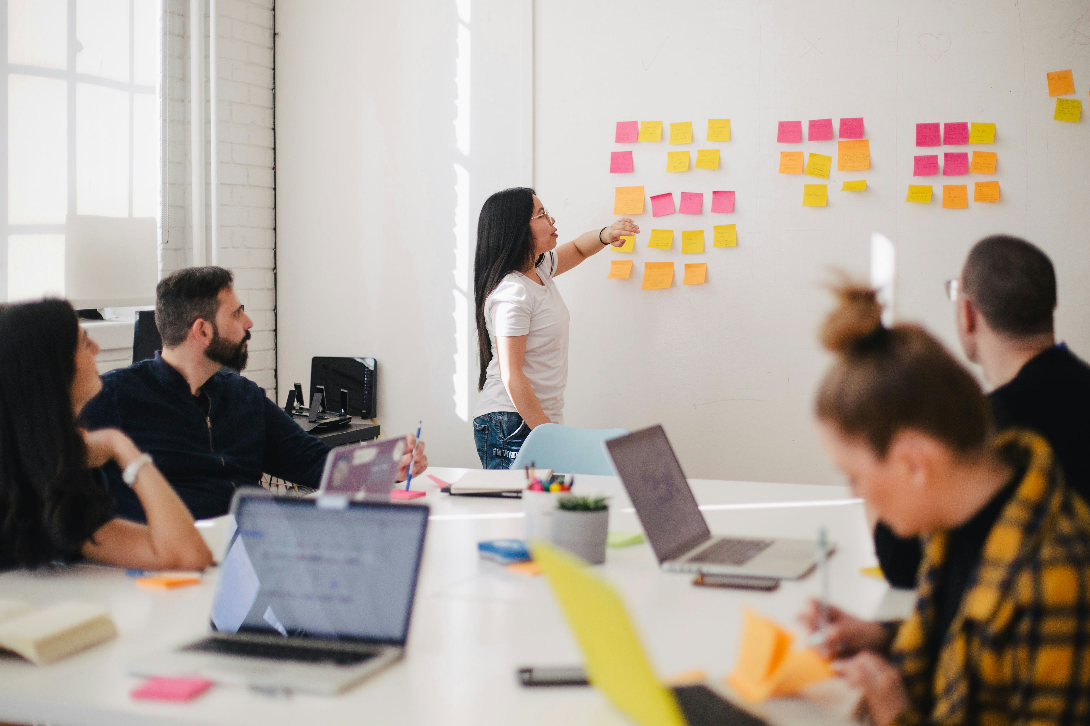 group of people in room looking at post-its with laptops
