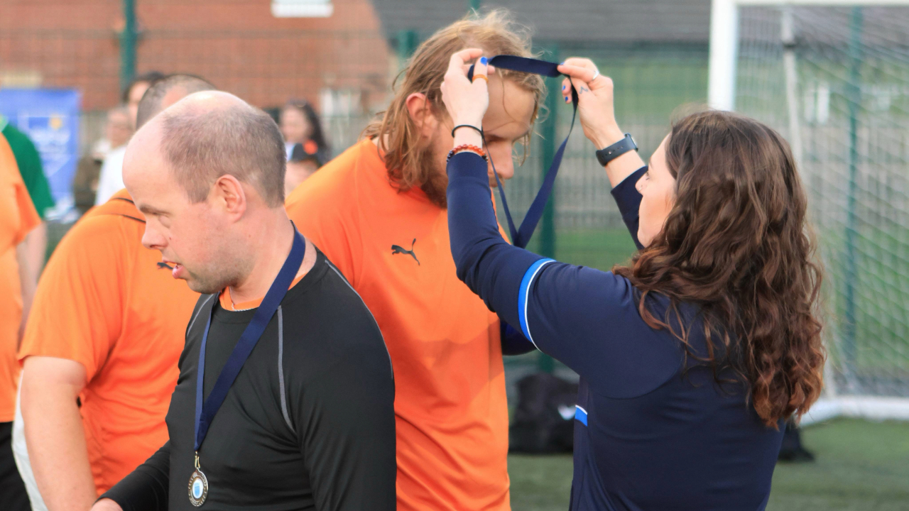 A graduate handing out medals to a football team