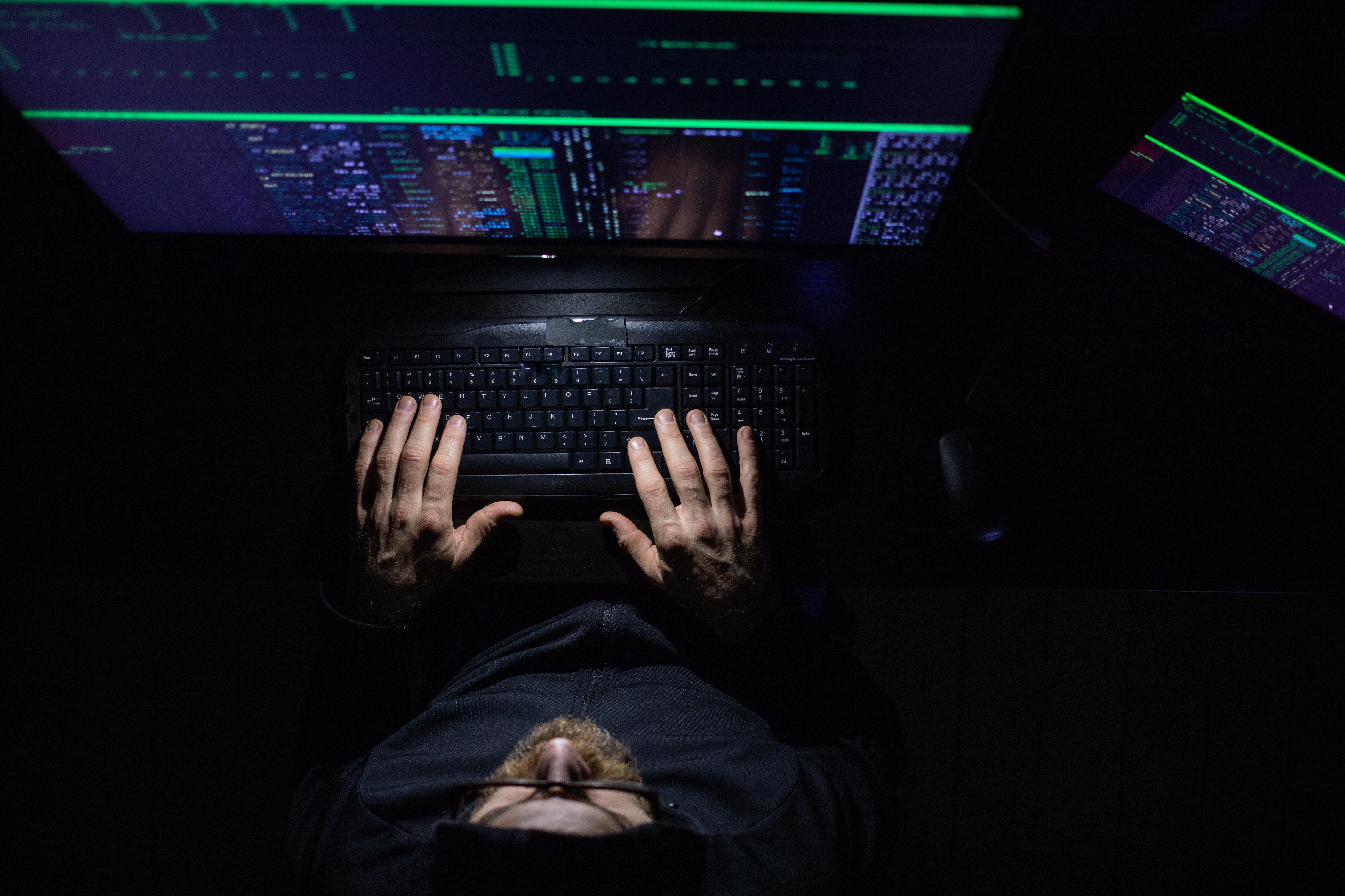 Cybersecurity student working on computer code in a dark room, learning ethical hacking and digital security skills in a Cybersecurity BSc degree program.