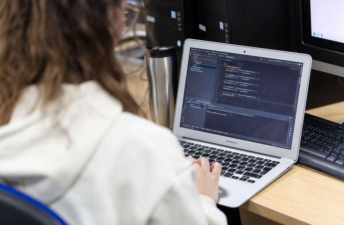 Student coding on a laptop during a Cybersecurity (Conversion) MSc course in a computer lab.
