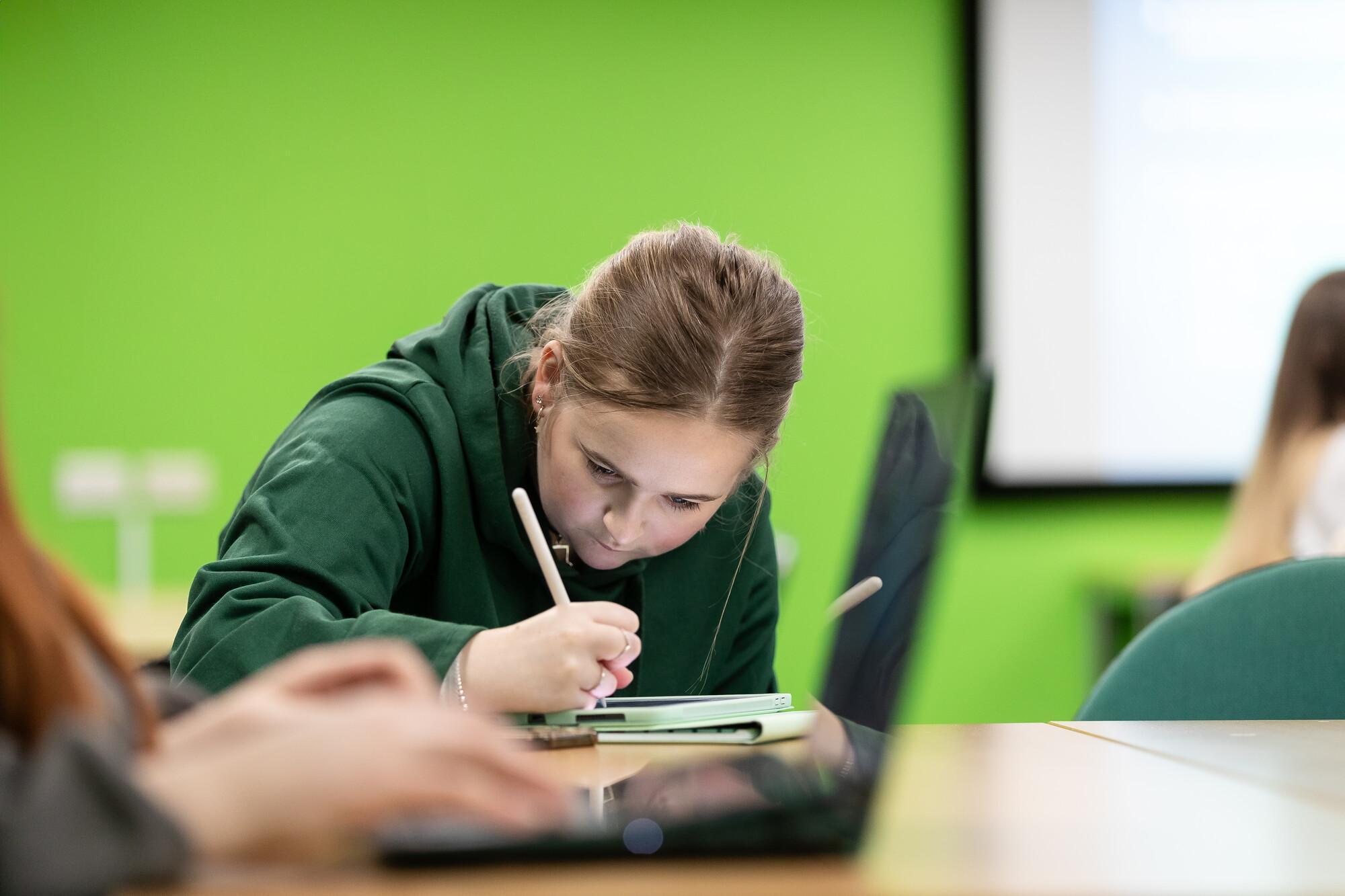 Criminology and Psychology BSc (Hons) student taking notes in class, learning about crime, behaviour, and psychological theory.