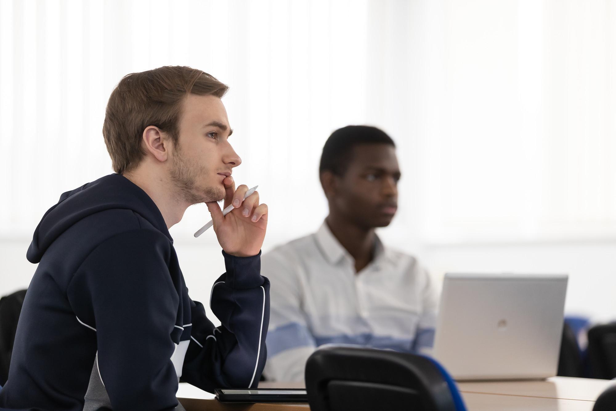 Mathematics with Finance students engaged in a university lecture, using laptops and digital tablets to analyse financial data and solve quantitative problems in a modern classroom.
