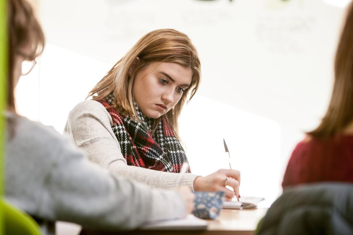 Creative Writing BA student focused on writing in a classroom, developing storytelling and writing skills during a university creative writing workshop.