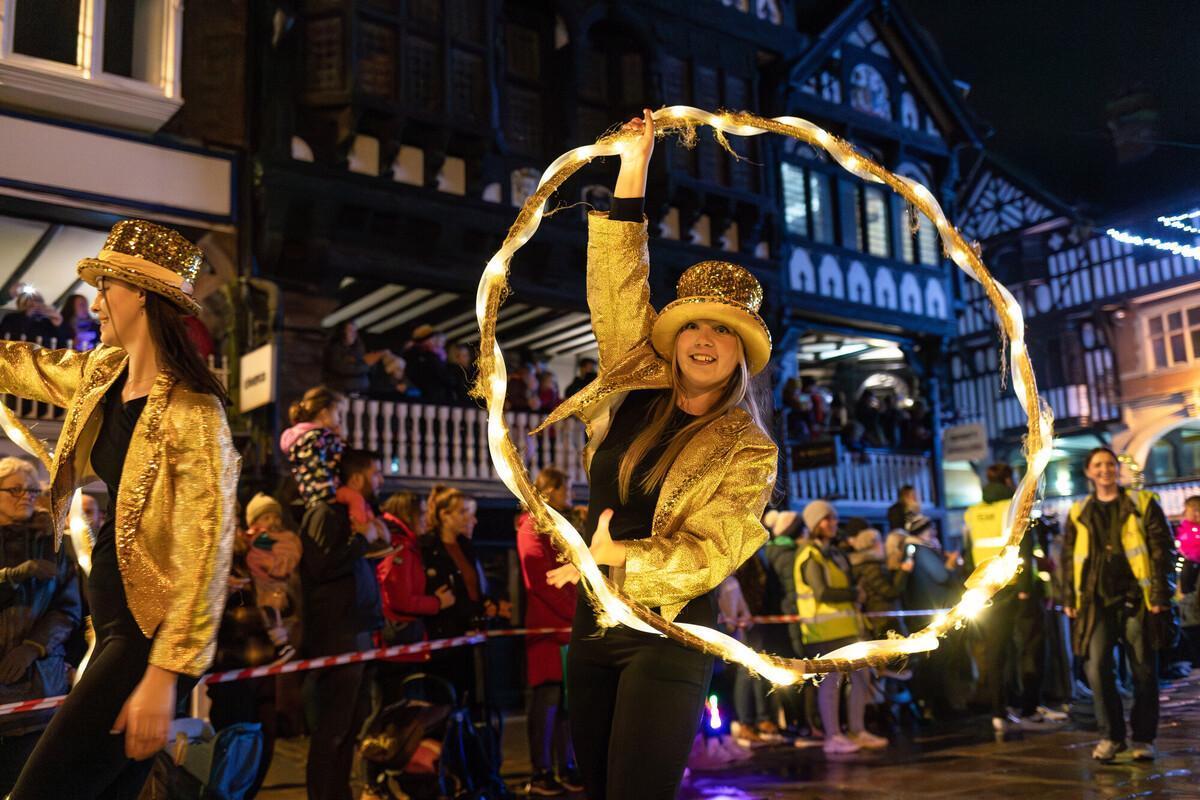 Dancers in glittering gold outfits perform with illuminated hoops during a vibrant city parade, capturing the energy, coordination, and creativity developed through the Events Management BA hons degree.