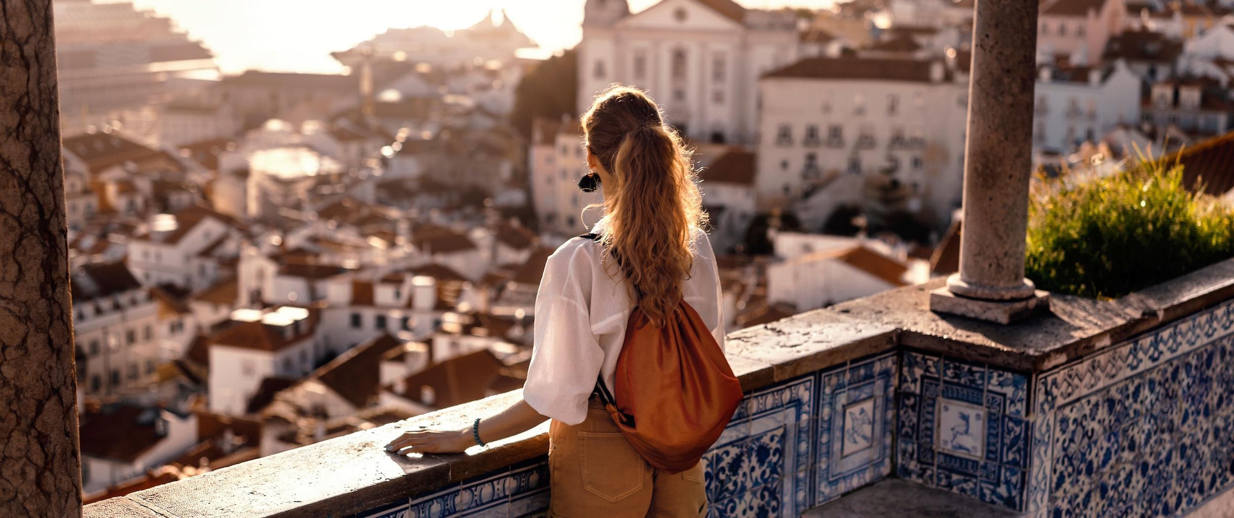 A Geography degree student with a backpack looks out over tiled rooftops and historic buildings while studying abroad.