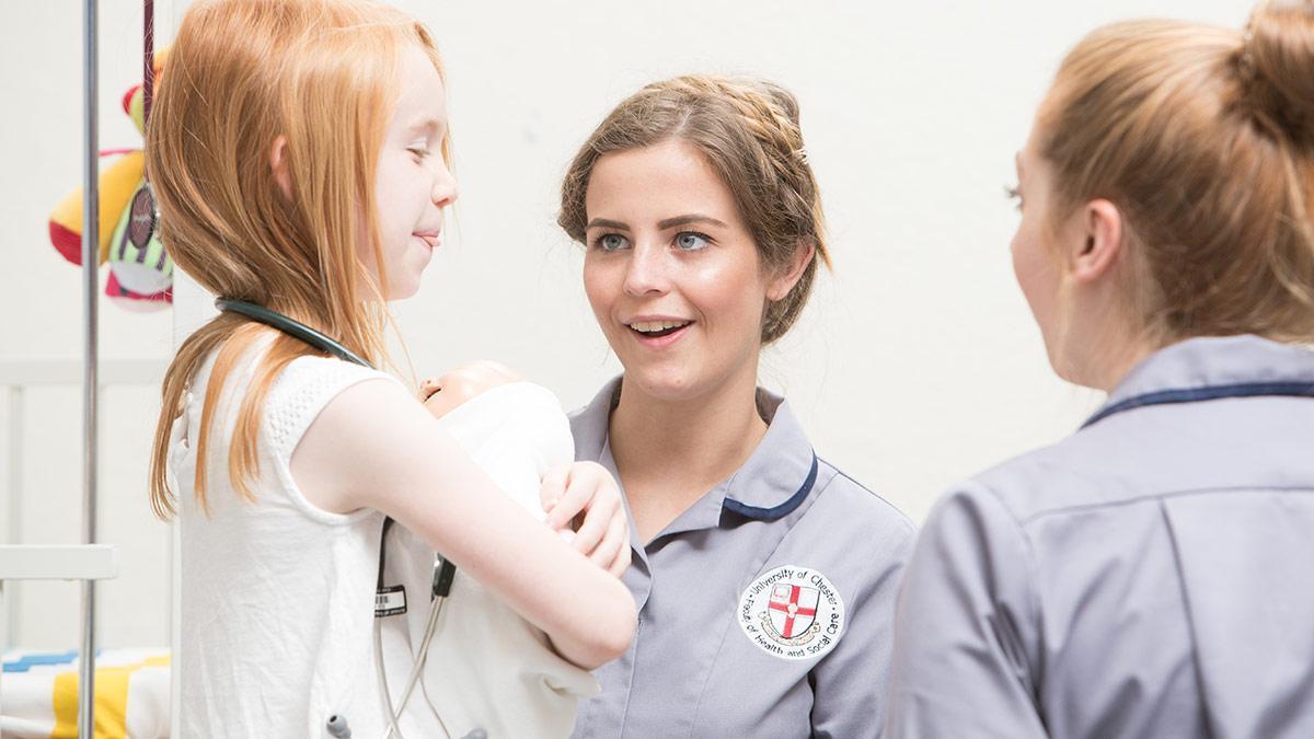 Nursing students interacting with a child in a clinical training setting, practising communication and care skills as part of the Mental Health and Children's Nursing MNurs (Hons) degree.