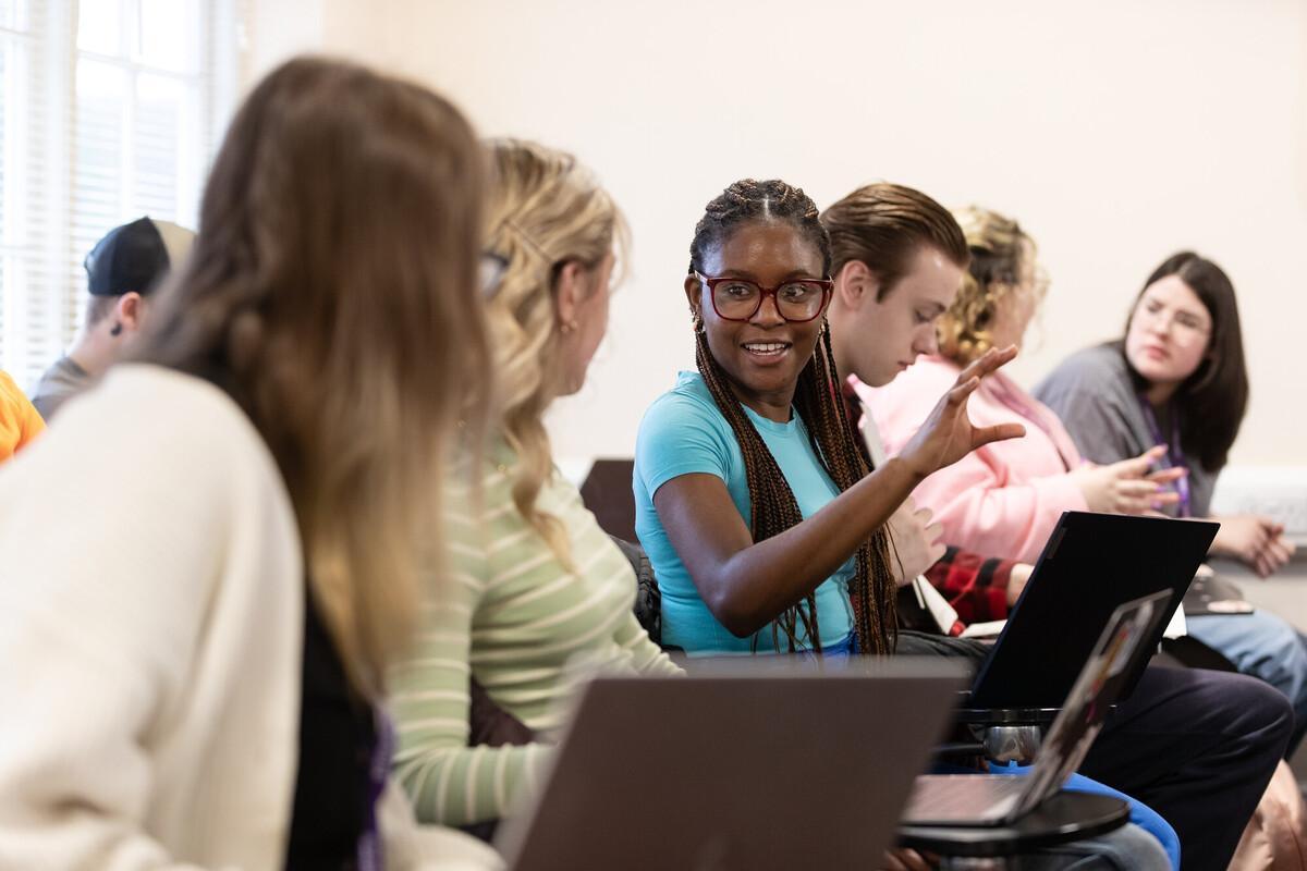 Students collaborate in a university seminar, discussing public health research and population wellbeing with laptops, reflecting the research-led learning experience of the Public Health MRes at the University of Chester.