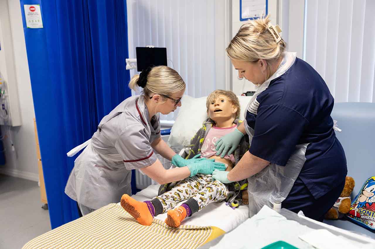 A nurse training an apprentice student nurse in child care.