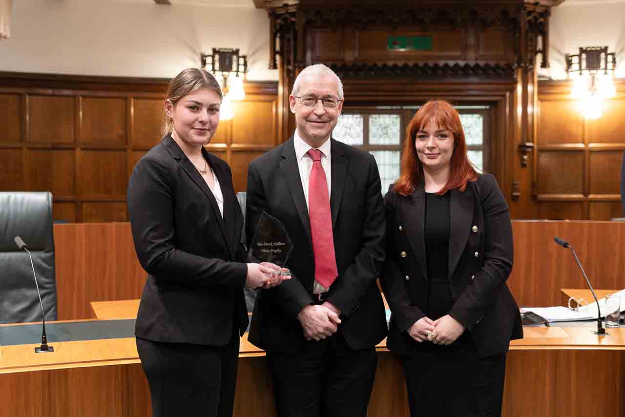 The winning team in The Supreme Court Moot, Sophie Kear (on left) and Chloe Lewis (on right) with The Right Honourable Lord Burrows, Justice of The Supreme Court of the United Kingdom.