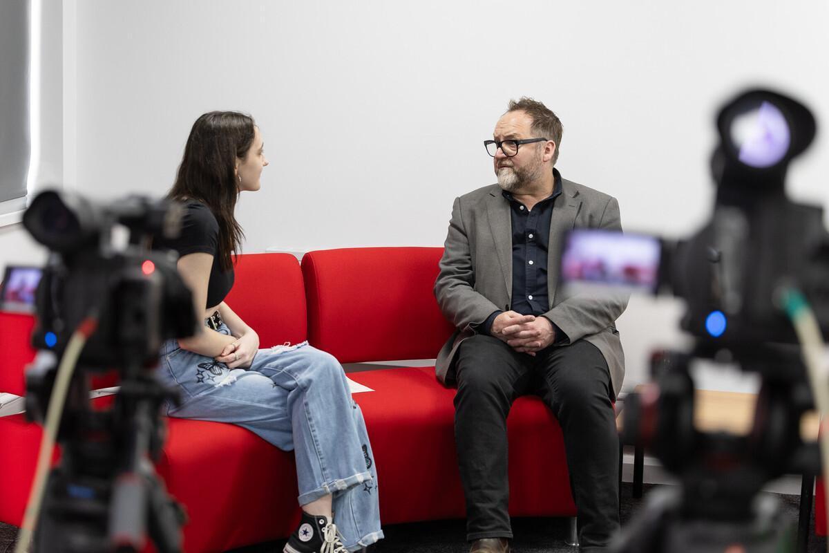 Journalism student interviewing a lecturer on camera in a university media studio, gaining hands-on experience for a BA Journalism degree.