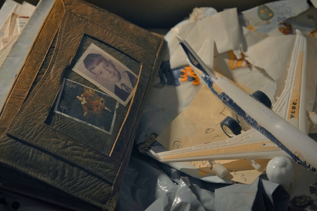 Screengrab from a film. The picture includes a wallet containing two photos of young children. Wrapping paper and a note with child's writing is obscured by a toy plane.