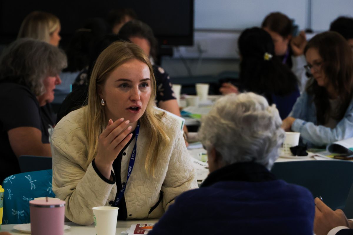 Two women in conversation, sat at a table.