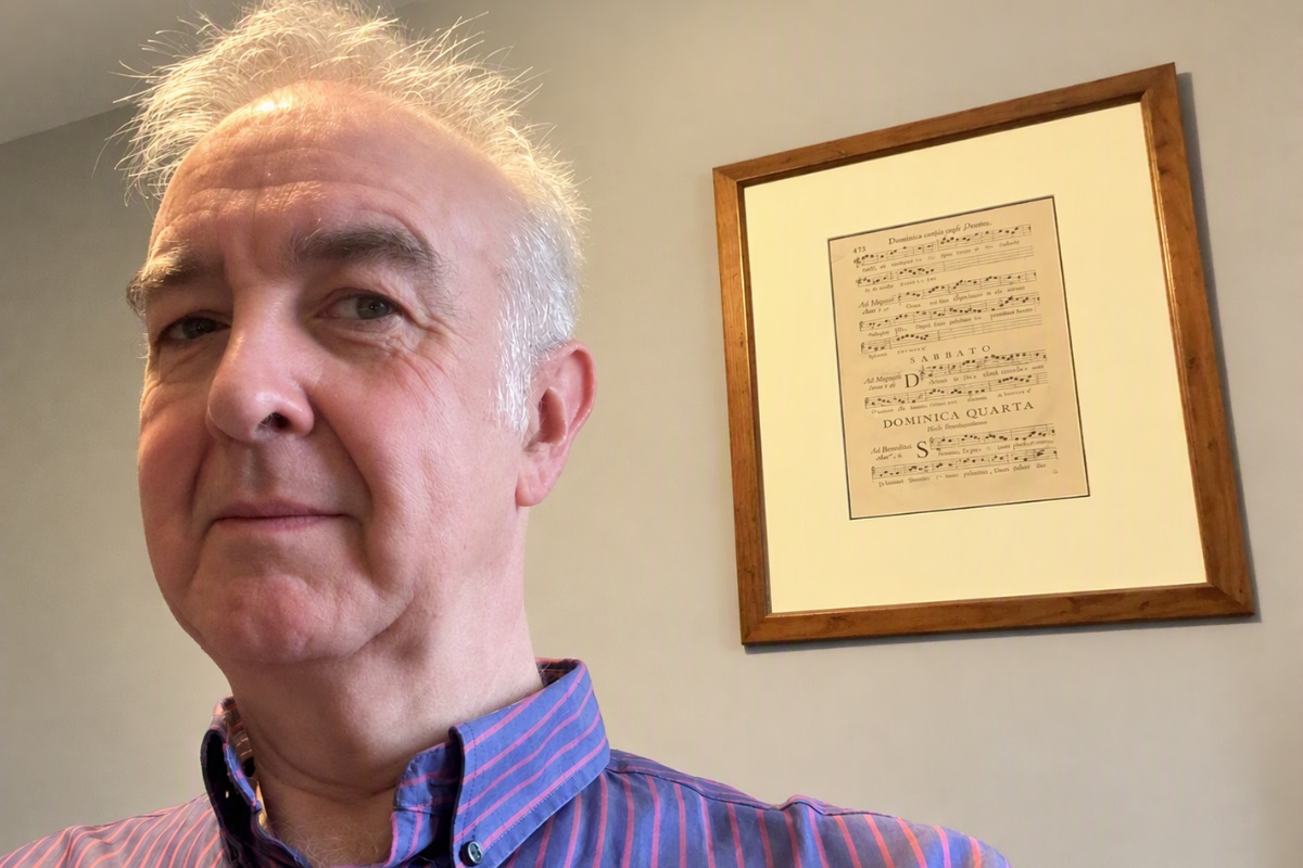 A head-and-shoulders picture of Darren Sproston looking at the camera. In the background is a framed music sheet on a wall.