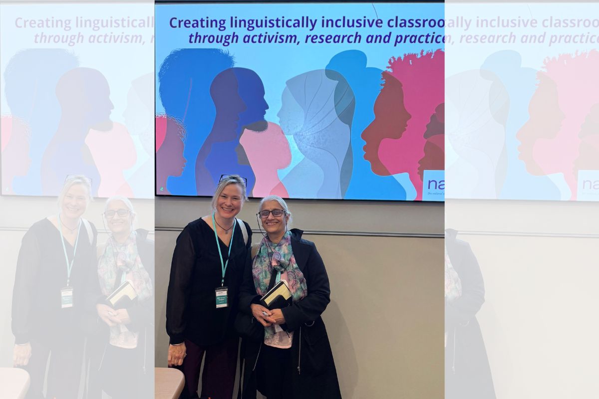 Niki Cooper-Robbins and Dr Chandrika Devarakonda standing in front of a projected image about one of the NALDIC32 talks.