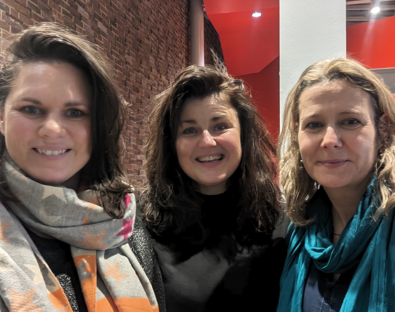 Three women facing the camera, smiling.