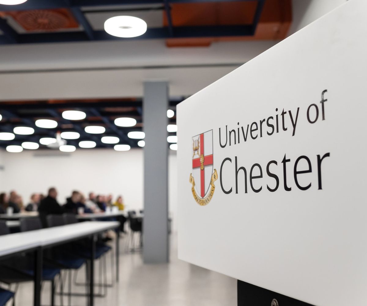 A University of Chester sign with students in the background.