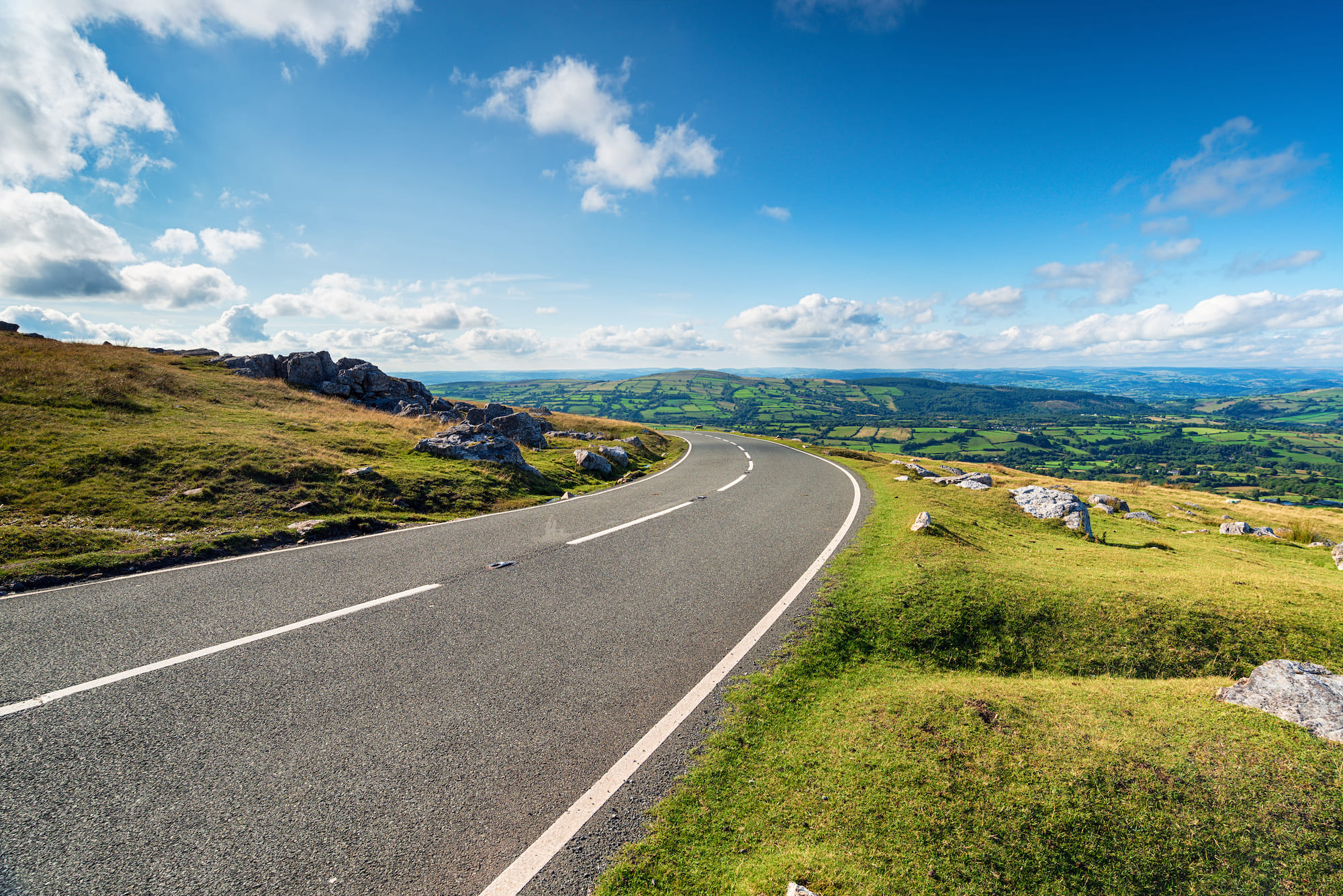 a rural road with blue skies and fields either side