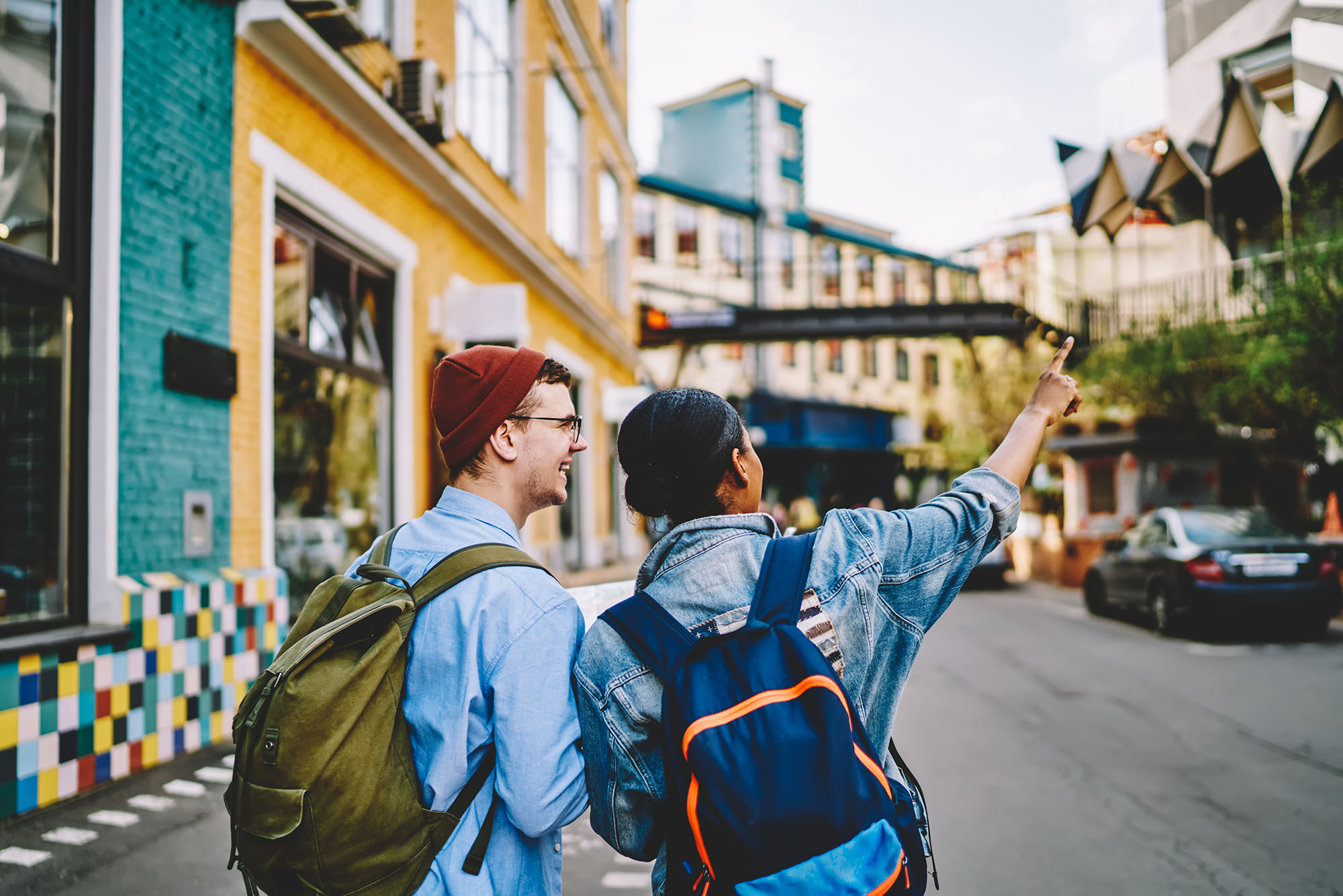 Back view of male and female backpackers enjoying live communication during travel experience for exploring city