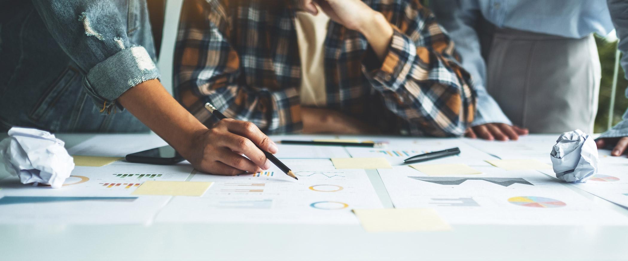Professionals collaborating on project plans, performance data and strategic documents, reflecting advanced leadership, programme delivery and project management skills developed on the Programme and Project Management MSc at the University of Chester.