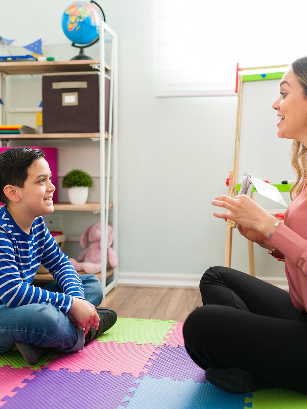 Side view of a caucasian boy making sounds during speech therapy.