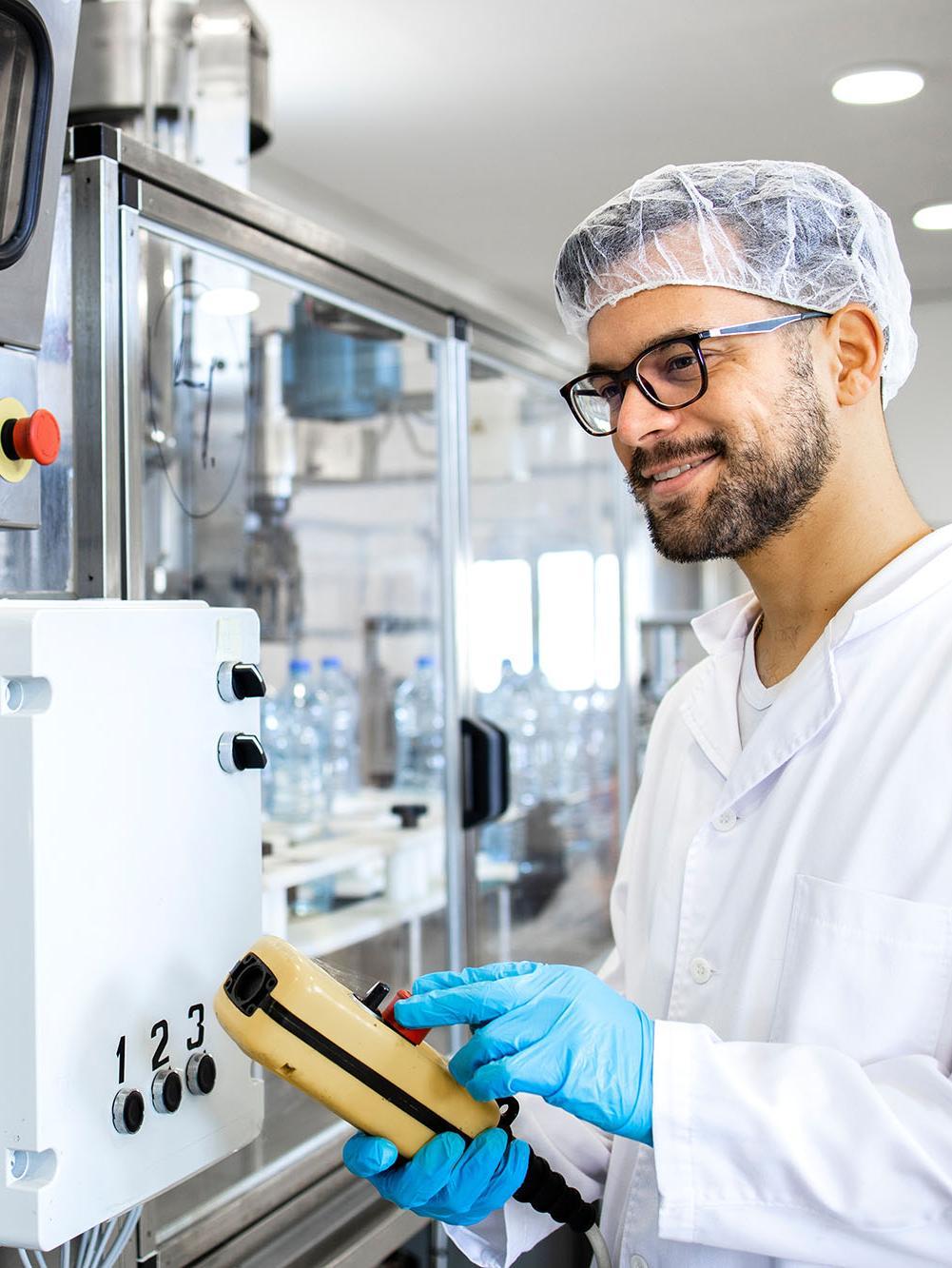 Worker or technologist operating industrial production machine in food processing factory.