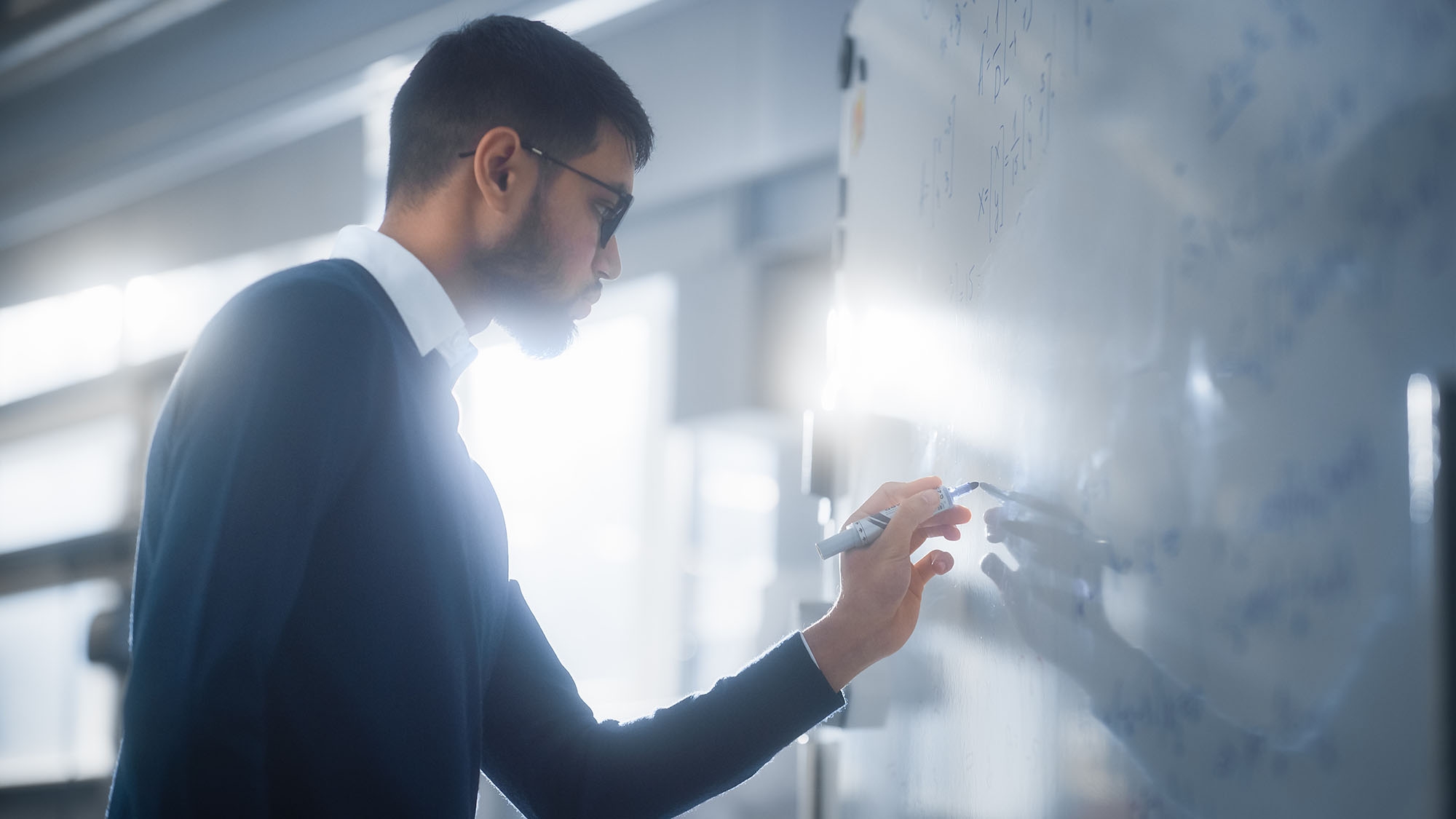 Black Male Scientist Solving Complex Mathematical Problems Standing and Writing Long Formulas on Whiteboard.