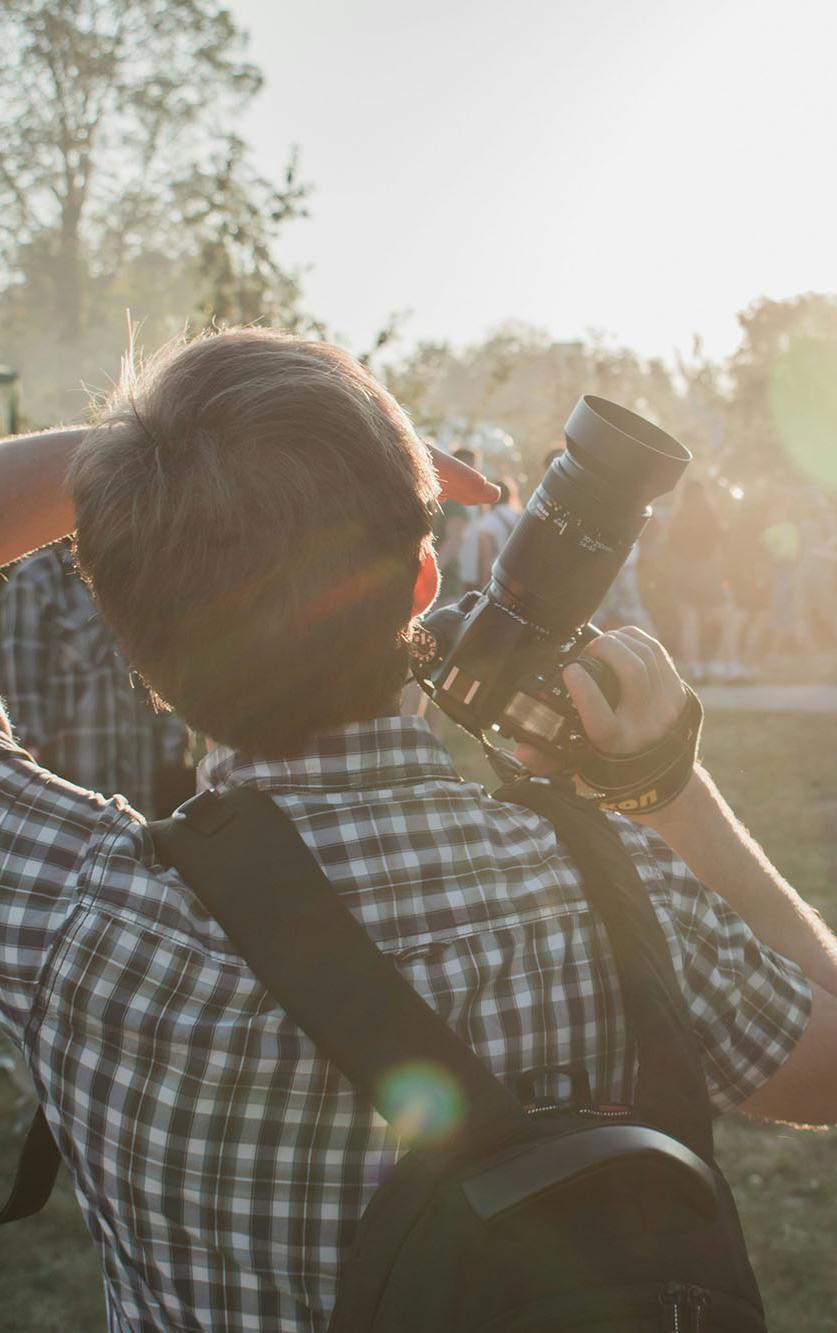A student photographer capturing a live outdoor music event at sunset, illustrating hands-on experience in music journalism and event coverage for the BA (Hons) in Music Journalism degree.