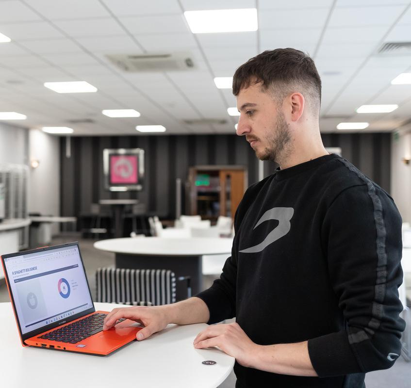 Professional Development by Negotiated Studies MA/MSc/MBA student using a laptop in a modern study space, showcasing flexible postgraduate learning, workplace development and career progression at the University of Chester.